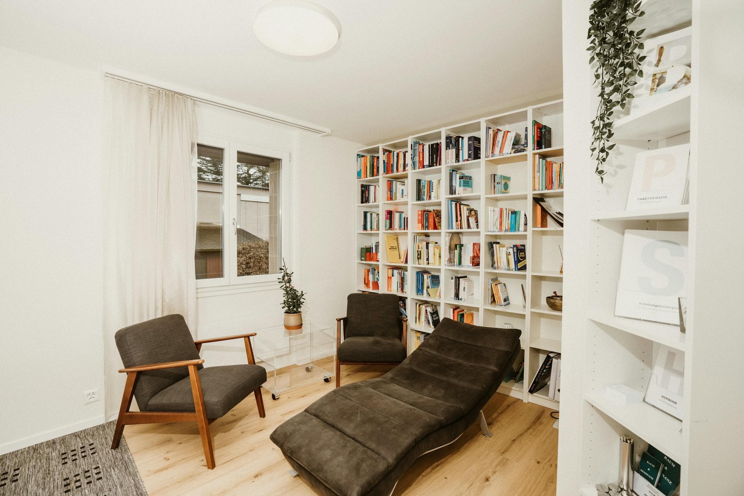 Une pièce de consultation claire, avec deux fauteuils, un divan et une bibliothèque